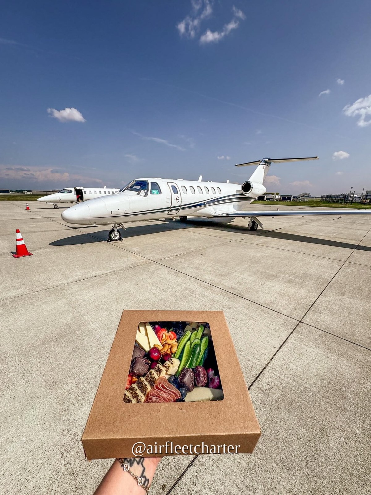 Charcuterie catering box on the tarmac beside a private jet